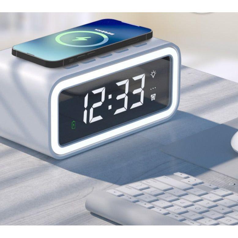 Zwarte digitale LED wekker met draadloze QI oplader en helder wit tijdweergave op een nachtkastje.
