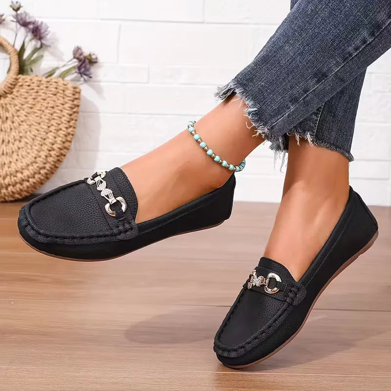 Elegante dames instappers met opvallend vlinderdetail. Stijlvolle zwarte platte schoenen, comfortabel en veelzijdig.