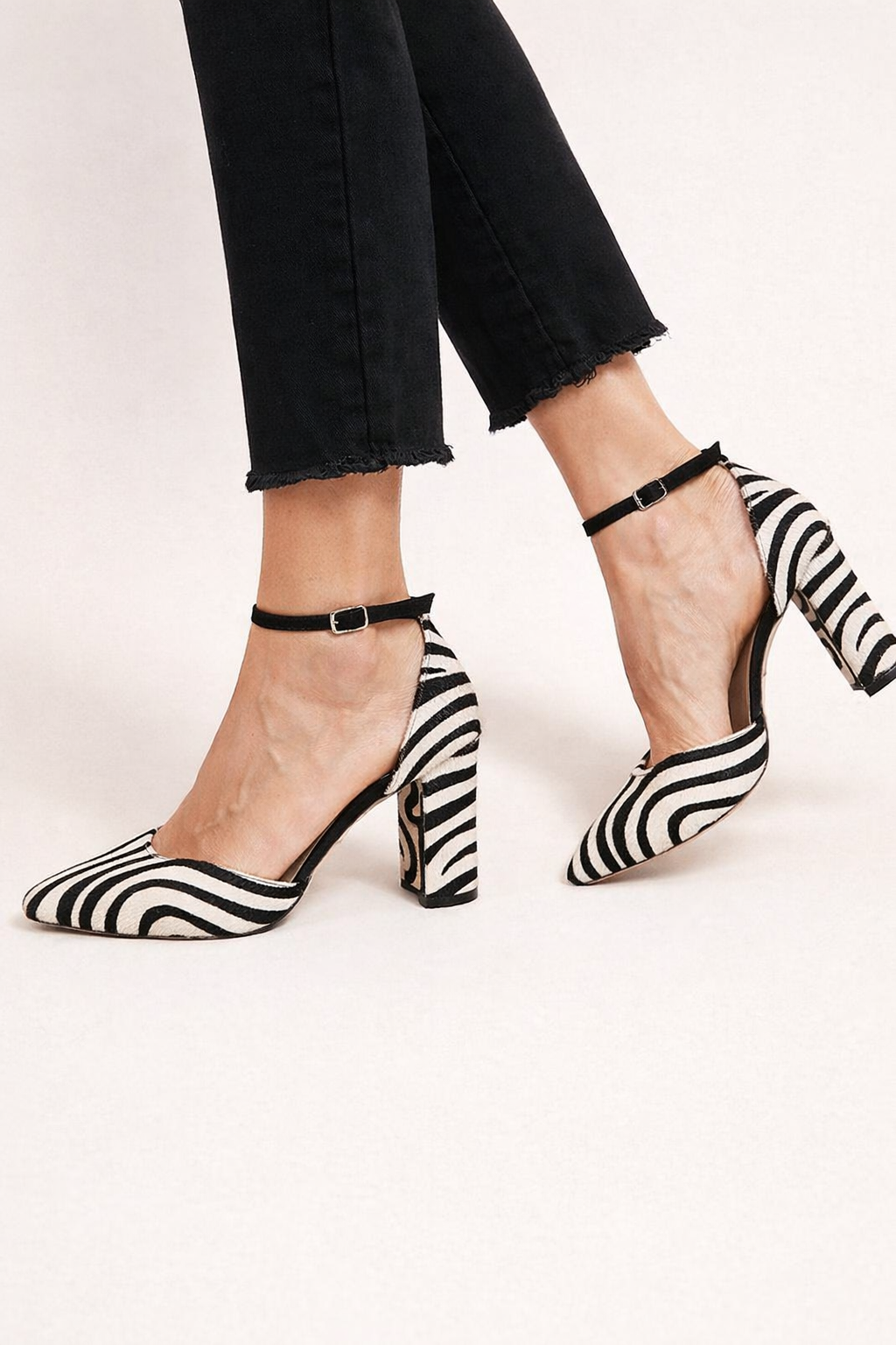 Zwartwitte damesschoenen met zebraprint, hoge hakken en een elegant enkelbandje, perfect voor uitgaan.
