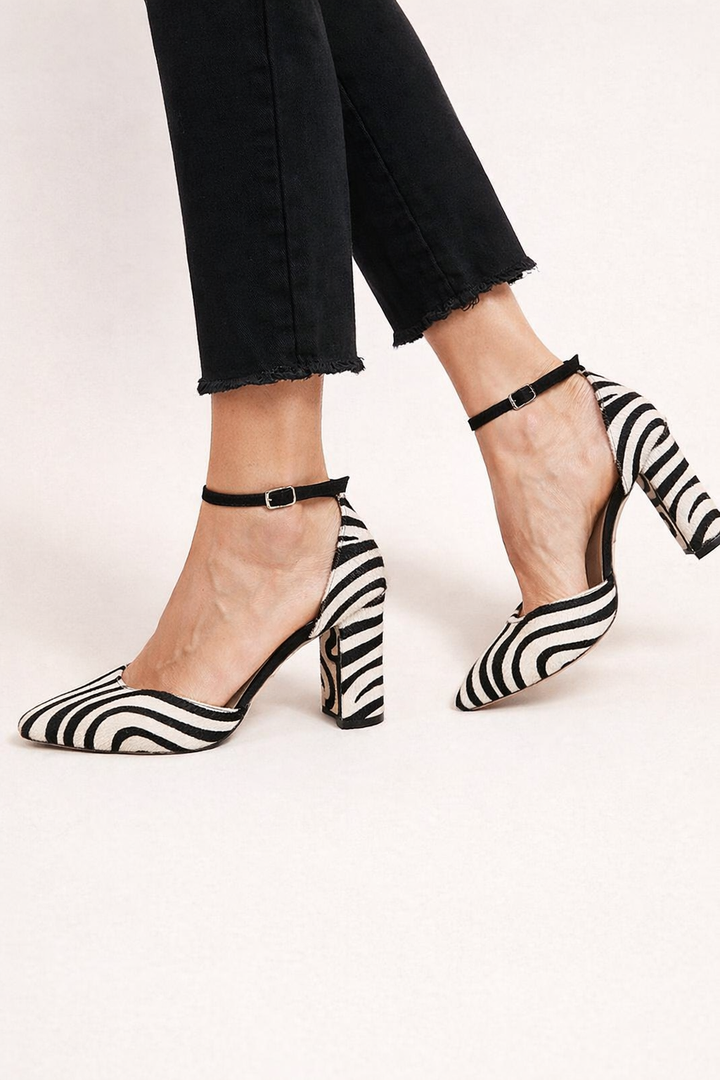 Zwartwitte damesschoenen met zebraprint, hoge hakken en een elegant enkelbandje, perfect voor uitgaan.
