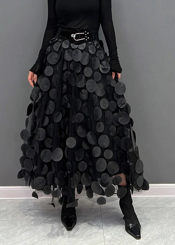 Vrouwelijke midi damesrok met zwarte stippenprint, zwierig vallend. Elegant en modieus voor zomerse dagen.